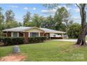 Single-story red brick home featuring a carport, mature trees, and a well-kept lawn at 3430 Stokes Ferry Rd, Salisbury, NC 28146