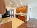 Bright kitchen featuring granite countertops, wood cabinets, and black appliances, open to the dining area at 4143 Kenton Glenn Nw Ct, Concord, NC 28027