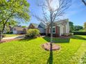 Attractive home exterior with well-kept lawn, mature trees, and a side-entry two-car garage on a bright sunny day at 4656 Chaucer Nw Pl, Concord, NC 28027