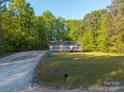 Quaint home on a spacious lot with a long driveway surrounded by lush greenery at 5039 Pine Springs Dr, Bessemer City, NC 28016