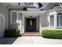 Elegant front entrance with a decorative glass door, flanked by manicured shrubs and brick steps at 5335 Lower Shoal Creek Ct, Charlotte, NC 28277