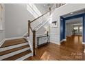 Bright foyer showcasing hardwood floors, a staircase with white railings, and decorative wainscoting at 11304 Preservation Ln, Charlotte, NC 28278