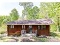 Back exterior showcasing the rustic wood facade and small deck, surrounded by mature trees at 1278 Island Creek Dr, Troy, NC 27371