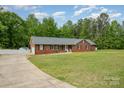 Lovely red brick home with attached garage, long driveway, and green lawn surrounded by beautiful trees at 1376 Garland Ln, Lincolnton, NC 28092
