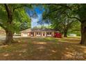 Quaint single-story home nestled among mature trees with a brick and siding facade, a garage, and well-kept landscaping at 2007 Green Peach Rd, Lancaster, SC 29720