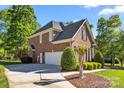 A side view of a brick two-story home showing the garage and long driveway at 204 Limerick Dr, Matthews, NC 28104