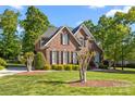Beautiful two-story brick home featuring black shutters, arched windows, manicured landscaping, and lush green lawn at 204 Limerick Dr, Matthews, NC 28104