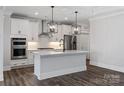 Kitchen with white cabinets, stainless appliances, center island with seating and modern pendant lighting at 2081 Fordhill St, Rock Hill, SC 29732