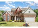 Inviting brick home featuring a well-kept front lawn, garden beds, and attached two-car garage at 3007 Sandbox Cir, Indian Trail, NC 28079