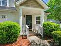 Close-up of home's front porch, showcasing the entry door, and landscaped shrubs at 6647 Vlosi Dr, Charlotte, NC 28226