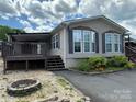 Charming home featuring well-maintained landscaping, flowerbeds, dark shutters, covered porch, and a fire pit at 116 Dove Ln, New London, NC 28127