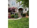 A welcoming front entrance featuring stone accents, a covered porch, and beautiful flowering shrubbery at 1418 Lonan Dr, Waxhaw, NC 28173
