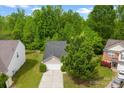 Aerial view of house with a one-car garage, driveway, and a well-maintained lawn, surrounded by lush trees at 1457 Mandy Place Ct, Charlotte, NC 28216