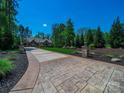 Beautiful long driveway leading to a brick home with meticulously landscaped grounds and stone pillar lamps at 1579 Sunset Pointe Dr, Salisbury, NC 28146