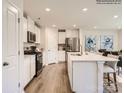 Bright kitchen features stainless steel appliances, white cabinets, an island with sink and chairs, and hardwood floors at 2101 Columbidae Ln, Gastonia, NC 28052