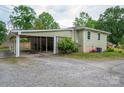 View of the side yard with a covered carport, gravel driveway and green shrubbery at 400 Houser St, Cherryville, NC 28021