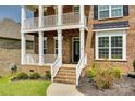 Close up showing covered front porch and entrance featuring brick stairs, dark door, and manicured landscaping at 4704 Amberside Dr, Rock Hill, SC 29732