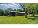 Brick ranch home with metal roof, screened in porch, and detached garage on a green lawn at 4815 Rifle Range Rd, Conover, NC 28613