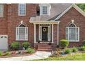 Inviting front entryway with a black door, decorative wreath, and colorful flowerbeds at 5775 Monticello Nw Dr, Concord, NC 28027