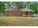 Charming brick home with a covered porch, yellow front door, green shutters, and mature landscaping at 6558 Covecreek Dr, Charlotte, NC 28215