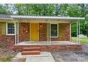 Inviting brick home with covered front porch, yellow front door, and well-maintained landscaping at 6558 Covecreek Dr, Charlotte, NC 28215