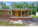 Inviting brick home with covered front porch, yellow front door, and well-maintained landscaping at 6558 Covecreek Dr, Charlotte, NC 28215