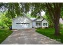 Bright white exterior featuring an attached two-car garage, long driveway, and lush green surroundings at 8200 Park Vista Cir, Charlotte, NC 28226