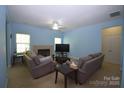 Comfortable living room with blue walls, a cozy fireplace, ceiling fan, and plush seating arrangements at 8200 Park Vista Cir, Charlotte, NC 28226