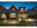 Exterior of a cozy brick home with illuminated landscape at twilight and covered front porch at 9319 Highclere Ct, Matthews, NC 28105