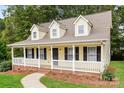 Low angle view of a yellow home with front porch and black door, surrounded by lush green trees at 1930 Manning Pl, Rock Hill, SC 29730