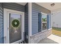 Close-up of a blue home's front door with a wreath and stone accents, complemented by black shutters at 2022 Mcdonald Dr, Stanfield, NC 28163