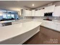 Bright kitchen with white cabinets, stainless steel appliances, a large island, and hardwood floors at 21110 Bank Fire Ln, Huntersville, NC 28078