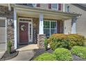 Inviting front porch featuring stone columns, a decorative wreath, and lush landscaping at 79115 Ridgehaven Rd, Lancaster, SC 29720