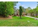 Charming brick home with a meticulously maintained lawn and mature trees at 8032 Turnberry Ln, Stanley, NC 28164
