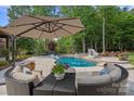 Lounge area with a large umbrella, table and chairs right by the pool and slide at 1102 Anniston Pl, Wesley Chapel, NC 28079