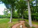 Lush backyard featuring a brick path, mature trees, and gazebo at 15546 Thompson Rd, Mint Hill, NC 28227