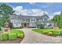Charming exterior showcasing meticulously landscaped grounds, a circular driveway, and a welcoming entrance at 299 Barber Loop, Mooresville, NC 28117