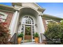 Elegant front door with a charming wreath, flanked by potted plants, set within a brick facade at 3420 Maryhurst Ln, Charlotte, NC 28226