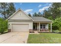 Charming single-story home with a garage and inviting front porch featuring craftsman-style details and landscaping at 8112 Mossy Rock Rd, Waxhaw, NC 28173