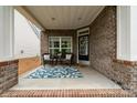 Inviting front porch with outdoor seating, brick columns, door with glass inserts and decor at 9802 Sky Vista Dr, Huntersville, NC 28078
