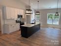 Bright kitchen with white cabinets, stainless steel appliances, large island and stylish pendant lighting at Lot 9 Lilly Pad Dr, Salisbury, NC 28146
