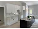 New kitchen features white cabinets with black hardware, subway tile backsplash, and a gray island with marble countertop at Lot 9 Lilly Pad Dr, Salisbury, NC 28146