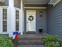 Inviting front porch with a wreath-adorned door, potted plants, and brick steps at 10009 Lattice Ct, Charlotte, NC 28269