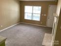 Bright living room featuring neutral walls, carpet flooring, a fireplace, and a large window that brings in natural light at 1012 Kings Mountain Ln, Gastonia, NC 28054