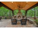 Inviting outdoor living space with stone fireplace and comfortable seating overlooking lush greenery at 1305 Anniston Pl, Wesley Chapel, NC 28079