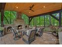 Inviting covered outdoor living space featuring a cozy fireplace, comfortable seating, and wood ceiling at 1305 Anniston Pl, Wesley Chapel, NC 28079