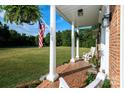 Inviting front porch featuring brick flooring, white columns, seating, and an American flag at 1488 Ernest Rd, York, SC 29745