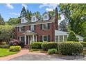 Beautiful brick home featuring a manicured lawn, complemented by lush landscaping and mature trees at 1949 S Wendover Rd, Charlotte, NC 28211