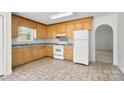 Well-lit kitchen featuring wood cabinets, a white refrigerator, and a view to the entry hall at 318 Huffman Rd, Gastonia, NC 28056