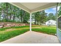 Covered patio looking out to a large backyard with a stone retaining wall at 3567 Farmfield Dr, Claremont, NC 28610